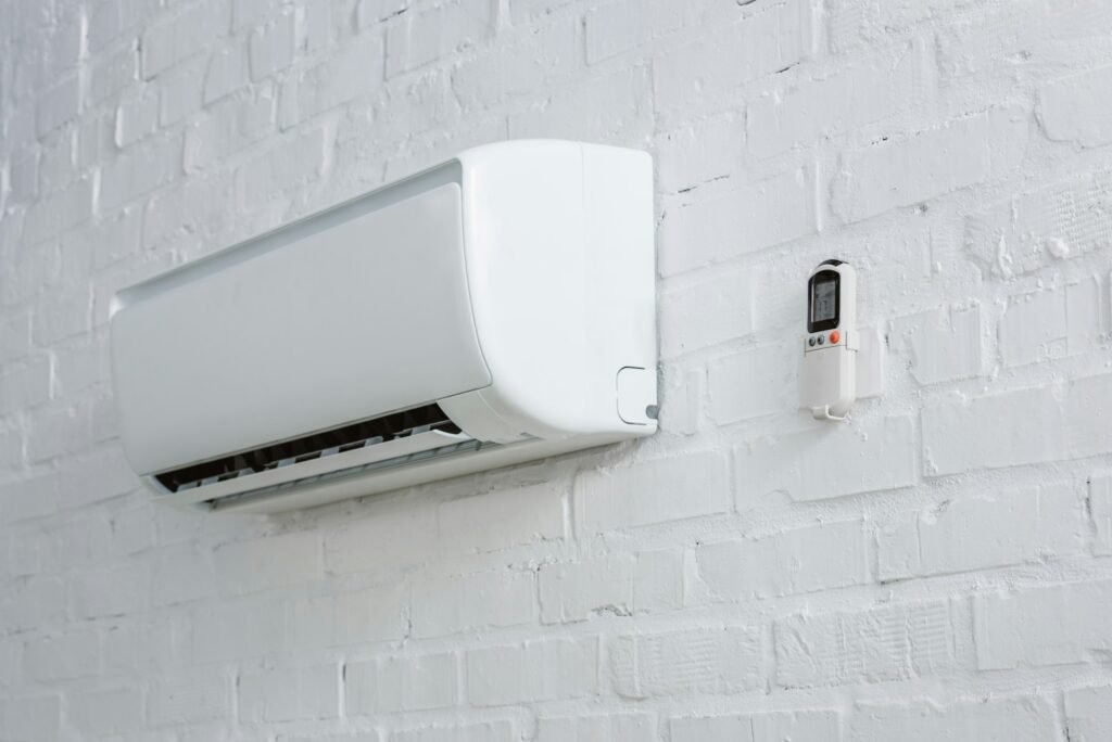 air-conditioner-hanging-on-white-brick-wall-with-remote-control in AC Repair and Maintenance shop