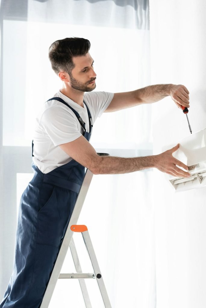 handsome-repairman-standing-on-stepladder-and-fixing-air-conditioner-with-screwdriver, AC repair services